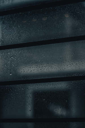 玻璃窗上的雨滴，帶有水平條框和背後模糊的城市燈光。