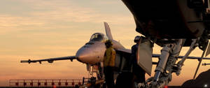 日落時分，航空母艦甲板上的戰鬥機及正在工作的機組人員。