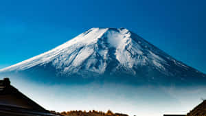 從傳統日本村莊觀看白雪覆蓋的富士山，天空清澈湛藍。