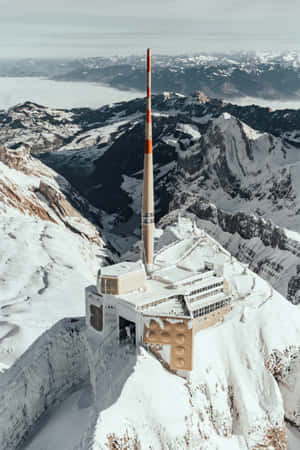 積雪山頂上的現代建築，帶有紅白相間塔樓。 — 美麗的日落動畫 壁紙