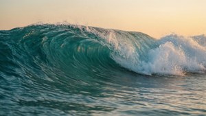 一道平靜的海浪在半空中翻捲，帶有藍綠色調與夕陽光芒。 — Awesome GIF 壁紙
