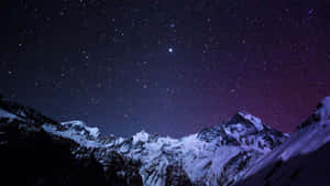在星空紫色夜空下，積雪的山脈與極光。