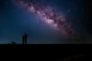 剪影情侶和狗在繁星夜空下，背景為銀河 — 天空景觀 壁紙