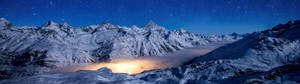 星空下的雪山山脈，下方是發光的山谷 — 冬天桌面 壁紙