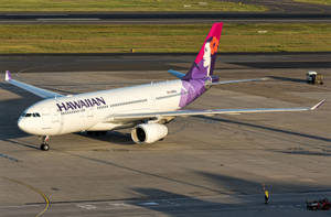 日落時分，夏威夷航空飛機在停機坪上與地勤人員一起。