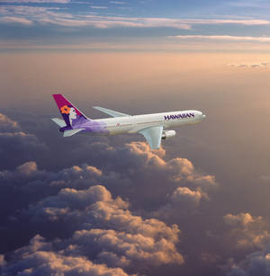 夏威夷航空的飛機在日落時分飛越金色雲層。