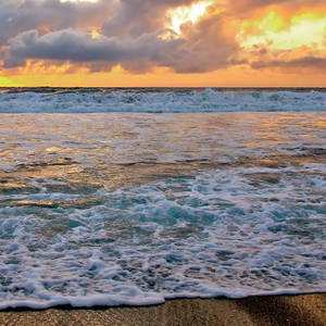 夕陽下海浪拍打沙灘，天空呈現火熱的橙色。