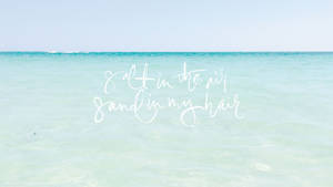 藍綠色海洋上的白色草書文字 salt in the air sand in my hair
