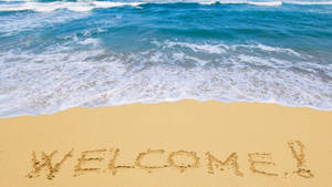 在海浪邊緣的沙灘上寫著WELCOME