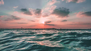 海洋上的日落，粉紅雲朵和藍綠色波浪