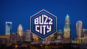 夜間城市天際線，有發光的建築物和中央的Buzz City標誌。 — 阿特蘭大鷹隊 壁紙