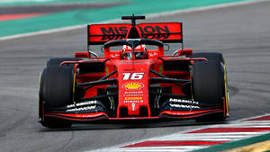 紅色法拉利F1賽車16號在帶有路緣的賽道上比賽。