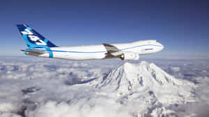 一架波音747飛機在雲層上方飛行，下方有一座積雪的山。