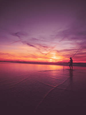 海灘上夕陽下漁夫拋線的剪影。