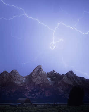 閃電擊中山峰，前景有穀倉，夜晚。 — 4:5 壁紙
