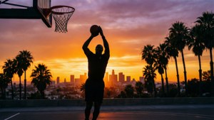 籃球運動員在日落城市景觀中投籃的剪影，伴有棕櫚樹。