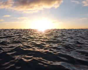 平靜的海面上夕陽西下，金色的光芒反射在波浪上。 — 水下 壁紙