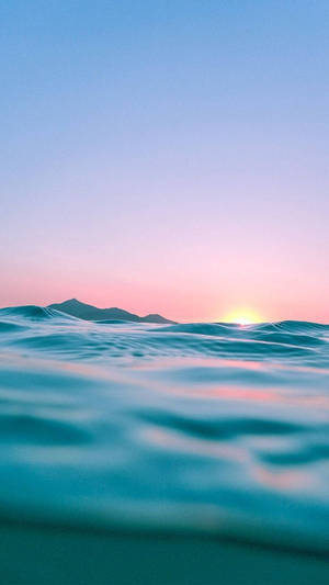 夕陽下的海浪，粉紅色和藍色的天空，遠山 — 沙灘 壁紙