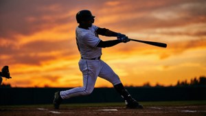 棒球運動員在夕陽下的球場揮棒