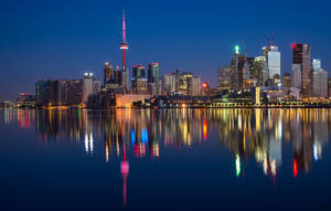 多倫多夜景，燈火通明的建築物倒映在水中。