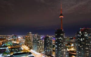 多倫多天際線夜景，CN塔亮起，周圍建築物閃爍。