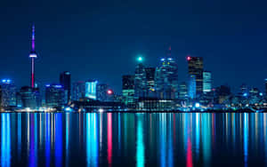 多倫多天際線夜景，色彩繽紛的燈光倒映在水面上。