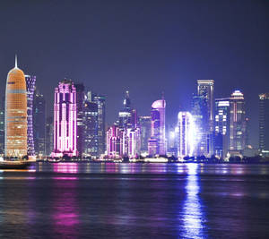 夜間城市天際線，色彩繽紛的燈光倒映在水面上。