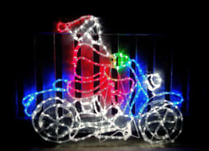聖誕老人在夜間騎著由彩色燈光組成的三輪車。 — AMOLED 壁紙