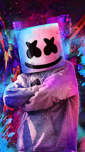 DJ Marshmello 戴著發光頭盔，雙臂交叉，站在色彩繽紛的塗鴉牆前。