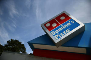 建築物上嘅Domino's Pizza招牌，背景係藍天同樹。