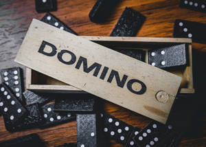 黑色多米諾骨牌散落在一個標有DOMINO的木盒周圍。 — 引擎 壁紙