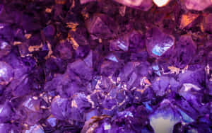 一簇紫色紫水晶晶體，帶有金色內含物，溫暖地發光。 — 珠寶 GIF 壁紙