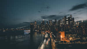 黃昏時分紐約市天際線，有發光的建築物和汽車的光軌。 — 夜景城市 壁紙