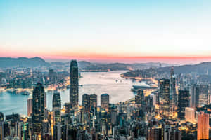 香港天際線在夕陽下，建築物燈光閃爍和海港水面。 — 夜景城市 壁紙