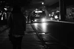 夜晚在城市人行道上獨自行走的人，巴士正在靠近。 — 城市景觀 壁紙