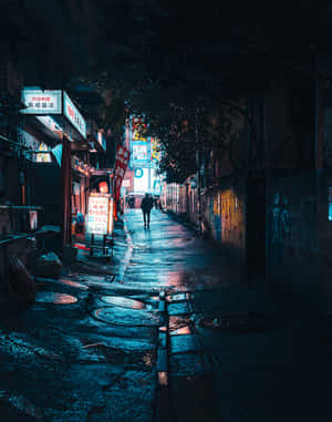 一個人在雨夜獨自走在霓虹燈照亮嘅城市小巷中。 — 暗夜城市 壁紙