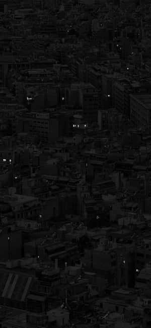 黑暗中帶有發光窗戶的密集城市的夜間鳥瞰圖。 — 深色iPhone壁紙