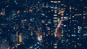 從空中視角看到的夜晚城市景觀，帶有發光的窗戶和明亮的街道。 — 夜景城市 壁紙