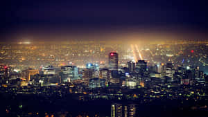 一座燈火通明的城市的全景夜景，擁有高聳的建築物和發光的街道。 — 5120x2880 壁紙
