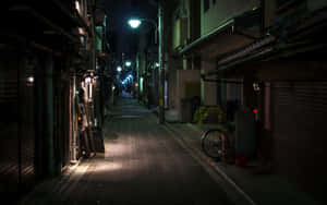 夜晚燈光昏暗的狹窄小巷，商店關門，旁邊停著一輛單車。 — 夜晚 GIF 壁紙
