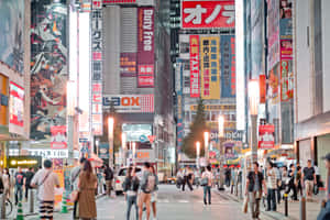 夜晚東京擠迫的街道，閃爍的霓虹燈牌和動漫廣告板。 — MacBook Pro M4 壁紙
