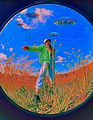 穿著綠色外套的人站在橙色花田中，藍天有UFO。