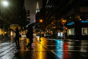 行人撐傘在發光的霓虹招牌下，走過夜晚雨濕的城市街道。 — 夜景城市 壁紙