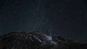 在繁星點點的夜空下，積雪的山峰。