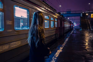 女子在濕漉漉的車站月台上看著火車，背景是紫色夜空 — 夜空 壁紙