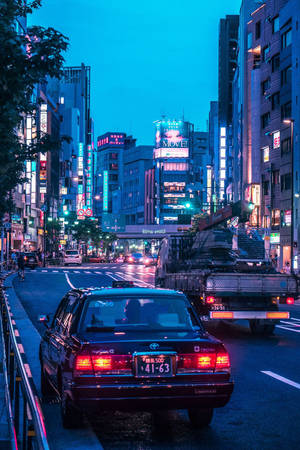 黃昏的東京街道，霓虹燈招牌和汽車在潮濕的路面上