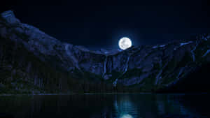 滿月映照在積雪的山峰上，倒映在夜晚平靜的湖面上。 — 夜晚 GIF 壁紙