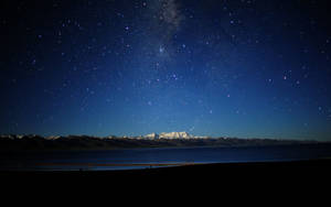 星空之夜，銀河在積雪的山峰和寧靜的湖泊之上。 — 天空景觀 壁紙
