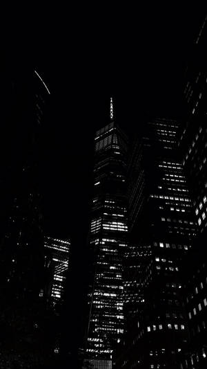 高聳的摩天大樓在夜間亮起，映襯著黑暗的天空。