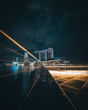 新加坡濱海灣金沙和海濱長廊的夜景，帶有發光欄杆和倒影。